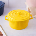 Yellow ceramic cooking pot with a lid on a light surface